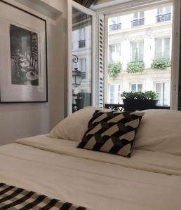 a bed with a black and white pillow in front of a window at Appartement Familial Au Coeur du Marais in Paris