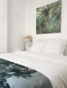 1 dormitorio con 1 cama blanca y una pintura en la pared en Appartement Familial Au Coeur du Marais, en París
