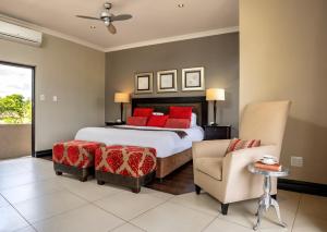 a bedroom with a bed with red pillows and a chair at Sofala Lodge in Mokopane