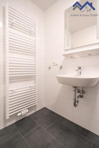 a white bathroom with a sink and a shower at Ferienapartments Junker & Auen in Weener