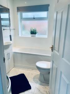 a bathroom with a toilet and a tub and a window at Deluxe Detached 3 bedroom house near Sheffield in Rotherham