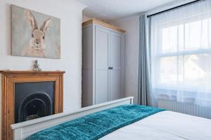 a bedroom with a bed with a fireplace and a window at Brook Cottage in Temple Ewell