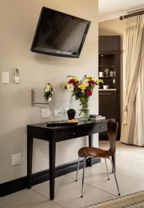 a black desk with a vase of flowers and a chair at Sofala Lodge in Mokopane