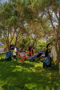 a group of people sitting in hammocks in a park at Studios Vrettos Beachfront Hotel in Plaka