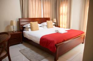 a bedroom with a large bed with a red blanket at D'Villa Rest Inn in Gaborone