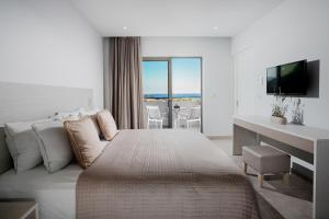 1 dormitorio con 1 cama y escritorio con TV en Porto Bello Beach Hotel, en Kardamaina