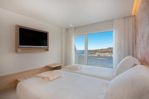 a white bedroom with a large window and a tv at Iberostar Selection Sábila - Adults Only in Adeje