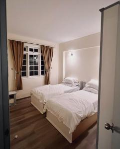 sypialnia z 2 łóżkami i oknem w obiekcie Blossom Silverpark Apartment w mieście Bukit Fraser