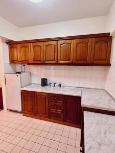 cocina con armarios de madera y nevera blanca en Blossom Silverpark Apartment en Bukit Fraser