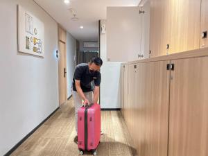 a man pulling a pink suitcase in a hallway at Yellow Bee Tanah Abang in Jakarta
