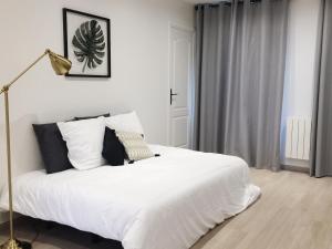 a bedroom with a bed with white sheets and a lamp at New Apartment in the Heart of Le Marais in Paris