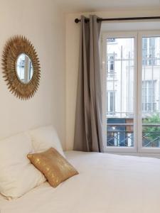 1 dormitorio con cama con espejo y ventana en New Apartment in the Heart of Le Marais en París