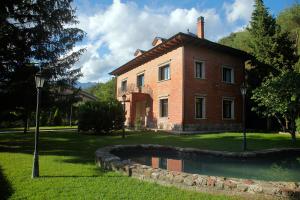 a large brick house with a pond in front of it at La Torre de Guardiola in Guardiola de Berguedà