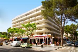 un grand bâtiment avec des voitures garées en face d'une rue dans l'établissement Arquus Park, à Salou