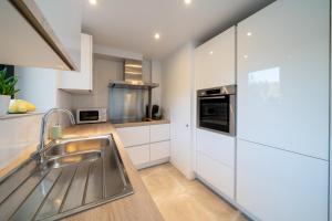 a kitchen with white cabinets and a sink at Au four et au jardin in Namur