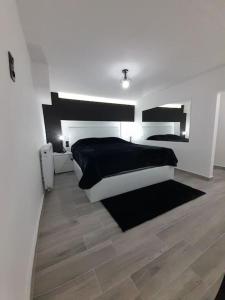 K&K Luxury Loft Apartment في سيريس: غرفة نوم بسرير أسود وبيض وأرضيات خشبية