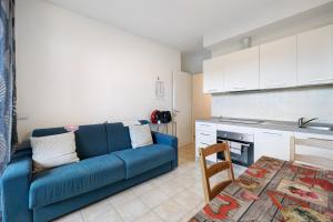een woonkamer met een blauwe bank en een keuken bij Condomino Alba Chiara 6 in Loano