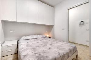 een witte slaapkamer met een bed en witte kasten bij Condomino Alba Chiara 6 in Loano