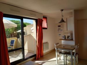 a kitchen with a table and chairs and a window at Studio Climatisé Résidence Odalys Saint Loup,piscine ,parking privé et superette in Cap d'Agde