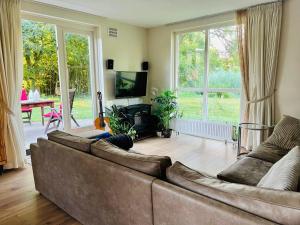 a living room with a couch and a large window at Supergezellig vakantiehuis met hele grote tuin bij Nijmegen in Ewijk