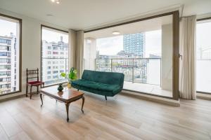 un soggiorno con divano verde e ampie finestre di Opera Square Apartments in the Center of Antwerp ad Anversa
