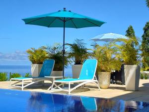 Petit Amour Villa, Seychelles في فيكتوريا: كرسيين ومظله بجانب مسبح