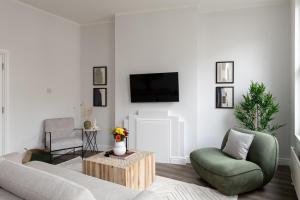 a living room with a couch and a chair and a tv at The Fulham Secret - Classy 5BDR Apartment in London