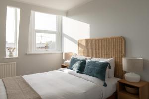 um quarto branco com uma cama com almofadas azuis em The Fulham Secret - Classy 5BDR Apartment em Londres