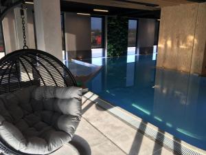 a swinging chair next to a swimming pool in a building at BalticSea Apartamenty in Sarbinowo