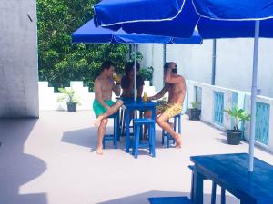 trois hommes assis à une table sous un parapluie dans l'établissement Blue Waves Madiha, à Matara