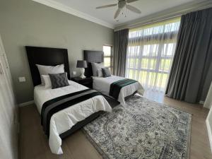 a bedroom with two beds and a large window at Sasavona Cottage - 349 Vaal de Grace Golf Estate in Parys