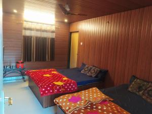 two beds in a room with wooden walls at altafs motel in Matheran
