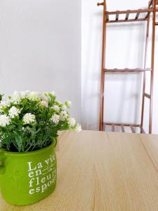 a green vase with white flowers sitting on a table at 32Sqm 1000x500wifi workplace long stay in Amphoe Phra Khanong