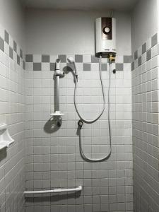 a shower in a bathroom with white tiles at 32Sqm 1000x500wifi workplace long stay in Amphoe Phra Khanong