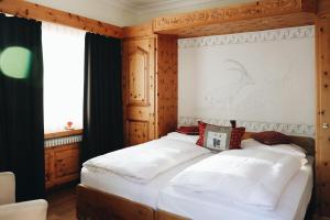 Schlafzimmer mit einem Bett mit einem Kopfteil aus Holz in der Unterkunft Hotel Nolda in St. Moritz