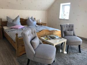 een slaapkamer met een bed en 2 stoelen en een tafel bij Ferienhaus ELPARE in Schleife