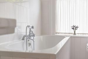 a white bathroom with a bath tub and a window at Poplar Farm House in Kent +25 photos