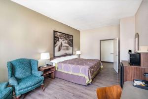 a hotel room with a bed and a chair at Super 8 by Wyndham Columbia in Columbia