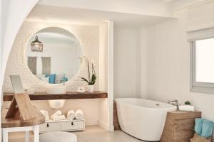Nikki Beach Resort & Spa Santorini في كماري: حمام مع حوض استحمام أبيض ومرآة