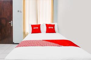 a bed with two red pillows on top of it at OYO 91926 Serayu Sumbersari Homestay in Jenggrik