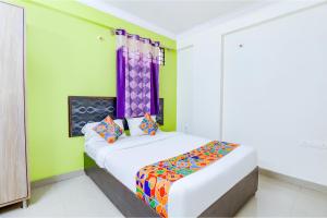 Un dormitorio con una cama con almohadas de colores. en FabExpress Ivory Pearl, en Bangalore