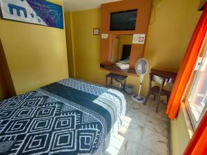 薩卡特卡斯的住宿－OYO Hotel Colón, Plaza Bicentenario, Zacatecas Centro，一间卧室配有一张床和一张带风扇的书桌