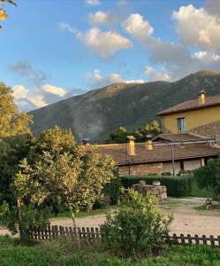 a house with a fence in front of a mountain at Agriturismo Is Conchisceddas in Gonnosfanàdiga