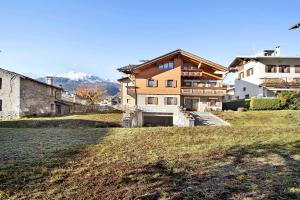 a house on a hill with mountains in the background at Baita al Pian Ginepro in Bormio