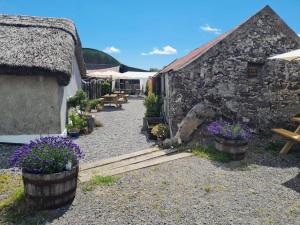 un edificio de piedra con bancos y flores delante de él en The Buzzard - 6 Person Family Glamping Cabin, en Dungarvan