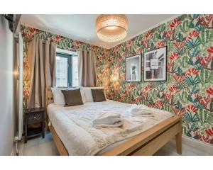 a bedroom with a large bed with floral wallpaper at Central Belfast Apartments: Citygate in Belfast