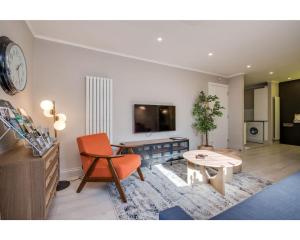 a living room with an orange chair and a table at Central Belfast Apartments: Citygate in Belfast