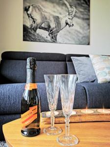 Una botella de champán y dos copas en una mesa. en Sankt Moritz Spirit Piz Bernina 5, en St. Moritz