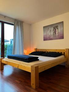 ein Holzbett in einem Zimmer mit einem großen Fenster in der Unterkunft Relaxklub villa s wellness in Třemošná