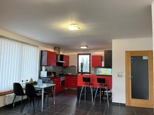 a kitchen with red cabinets and a table and chairs at Relaxklub villa s wellness in Třemošná